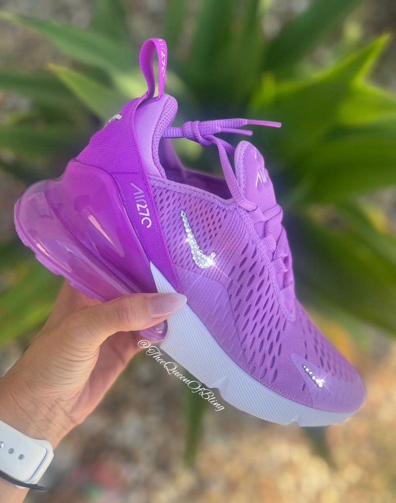 May include: Purple Nike Air Max 270 sneakers with a white swoosh and white sole. The swoosh is decorated with rhinestones.