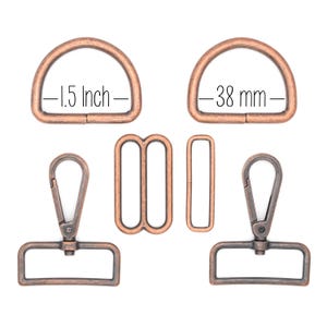 May include: A collection of antique bronze-colored metal hardware components, including two D-rings (1.5 inches or 3.8 cm), two swivel clasps, a rectangular slider, and a figure-eight connector. The components are displayed on a white background.