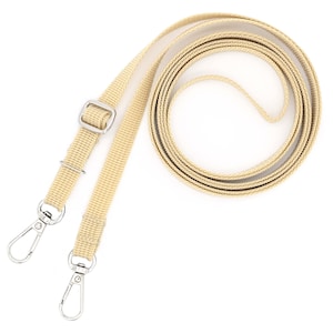 K&ouml;nnte beinhalten: Ein Paar beige verstellbare Riemen mit silbernen Metallschnallen und Haken. Die Riemen sind aus gewebtem Stoff und zum Befestigen an einer Tasche oder einem anderen Gegenstand bestimmt.