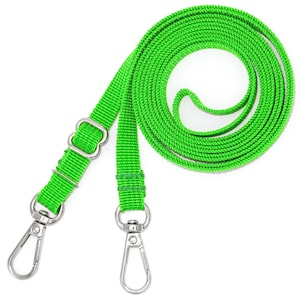 K&ouml;nnte beinhalten: Ein leuchtend gr&uuml;nes Lanyard mit zwei silbernen Drehclips. Das Lanyard ist aus gewebtem Material und etwa 3,8 cm breit.