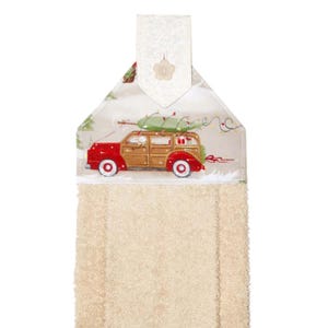 Puede incluir: Un pa&ntilde;o de cocina colgante de tem&aacute;tica navide&ntilde;a, beige y rojo. La parte superior presenta un coche familiar rojo y de madera que transporta un &aacute;rbol de Navidad verde. La toalla tiene un lazo beige con cierre de bot&oacute;n.