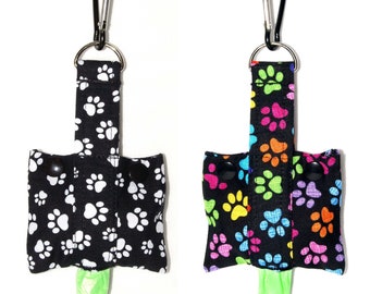 Fashion Tote Waste Bag Holder • Dog Poop Bag Dispenser With Clip • Bottom Dispensing For One-Handed Use • Pawprints on Black • Bags Included