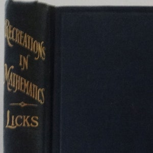 Op de afbeelding: Een donkerblauw boek met gouden letters op de rug. De titel is "Recreations in Mathematics" door "Licks". Het boek is uitgegeven door "Van Nostrand Company".