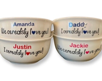 May include: Four white ceramic bowls with personalized messages. The bowls say "Amanda We cerealsly love you!"  "Justin I cerealsly love you!"  "Daddy I cerealsly love you!" and "Jackie We cerealsly love you!"