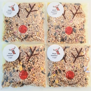 May include: Four clear bags of mixed grains and seeds, designed to look like reindeer faces. Each bag features a sticker with "Magic Reindeer Food" and a reindeer illustration. The bags have brown antler shapes and a red nose, perfect for Christmas.