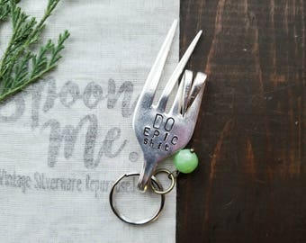 May include: A silver fork with the words "Do Epic Shit" stamped on it. The fork is attached to a key ring with a green bead.