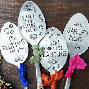 May include: Four silver spoons with different gardening-themed sayings engraved on them. The spoons are tied with colorful ribbons and are ready to be used as garden markers.