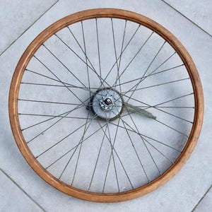 May include: A wooden bicycle wheel with a silver hub and spokes. The wheel is approximately 66 cm in diameter.