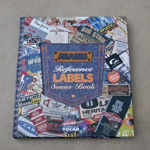 Könnte beinhalten: Ein Buch mit dem Titel "JEANS Reference LABELS Source Book" mit einem Jeans-Taschen-Design auf dem Cover. Das Cover ist eine Collage aus Vintage-Jeans-Etiketten und -Anhängern mit Marken wie Lee Cooper und Big Star.