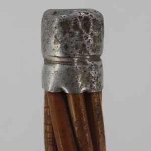 Pu&ograve; includere: Primo piano della parte superiore di un bastone con un tappo in metallo argentato. Il bastone &egrave; fatto di canne marroni intrecciate.