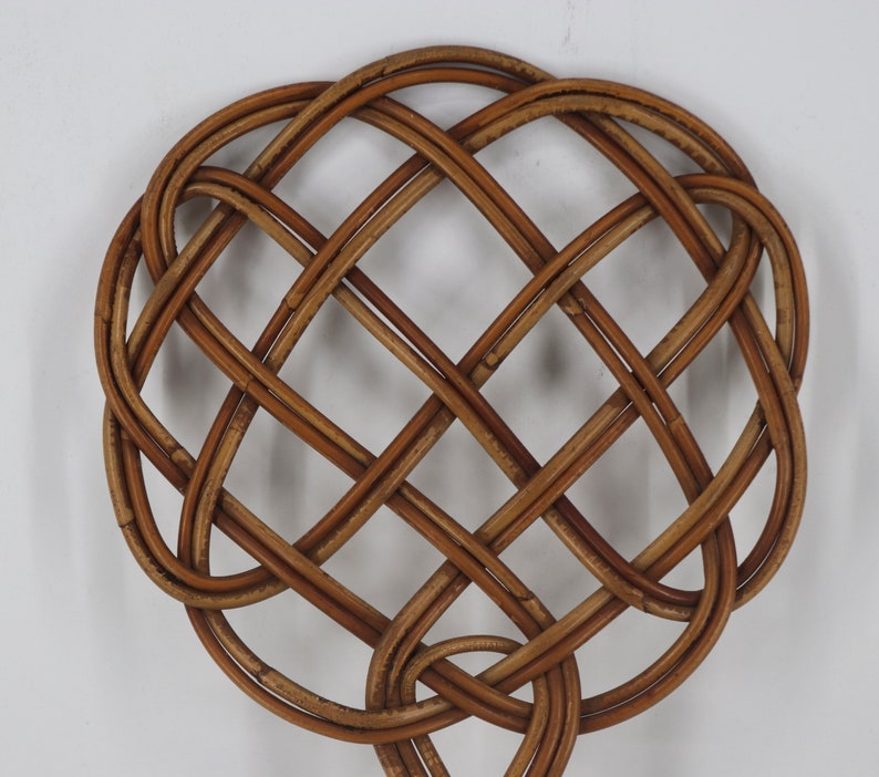Pu&ograve; includere: Un decoro da parete a forma di cuore in vimini intrecciato marrone con un motivo a croce.