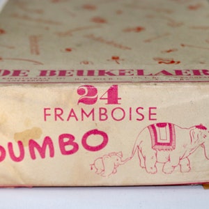 Könnte beinhalten: Eine Vintage-Schachtel mit 24 Himbeerbonbons mit einer rosafarbenen Dumbo-Illustration und dem Text "DE BEUKELAER 24 FRAMBOISE DUMBO".