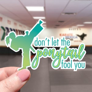 Don't Let The Ponytail Fool You - Glossy Water-Resistant Sticker - Water Bottle & Laptop Sticker - Karate Martial Arts Girl Kicker Fighter