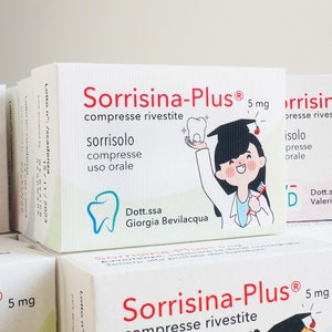 Può includere: Primo piano di tre scatole di compresse Sorrisina-Plus da 5 mg. Le scatole sono bianche con testo rosso e nero. Le scatole presentano un'illustrazione di cartone animato di una persona con un dente e uno spazzolino da denti. Il testo sulle scatole recita "Sorrisina-Plus 5 mg compresse rivestite".