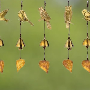 May include: A set of eight wind chimes featuring different bird and leaf designs. Each chime has a gold bell and a leaf-shaped charm. The birds are made of metal and have a gold finish.