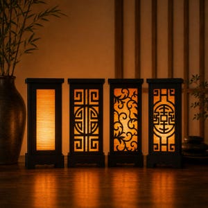 May include: Four black wooden lanterns with intricate cut-out designs. The lanterns have an orange glow emanating from within. The designs include geometric patterns and floral motifs. The lanterns are rectangular and stand on a wooden surface.