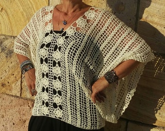 May include: A white crocheted top with a delicate floral pattern. The top has a wide, open neckline and a loose, flowing fit.