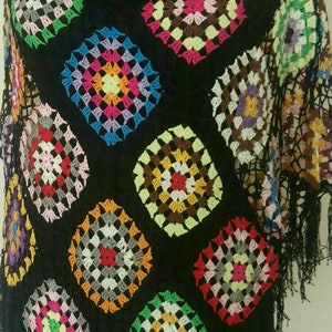 May include: A black crochet top with colourful square patterns and fringe trim.