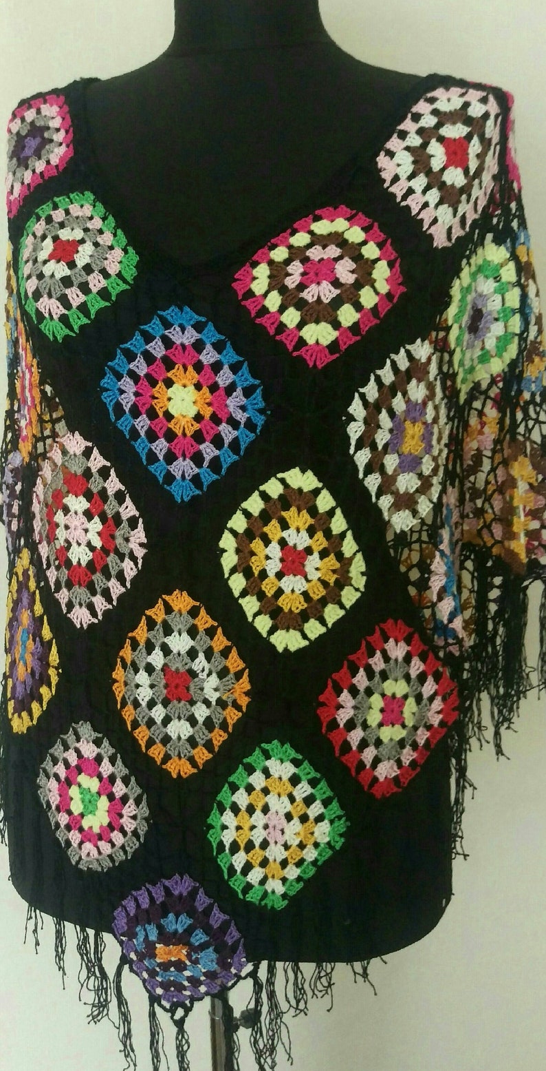 May include: A black crochet top with colourful square patterns and fringe trim.