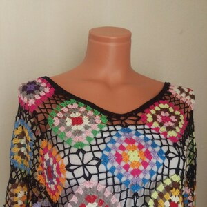 May include: A black crochet top with a colourful geometric pattern. The top is made of a lightweight, breathable fabric and features a loose, flowing fit.