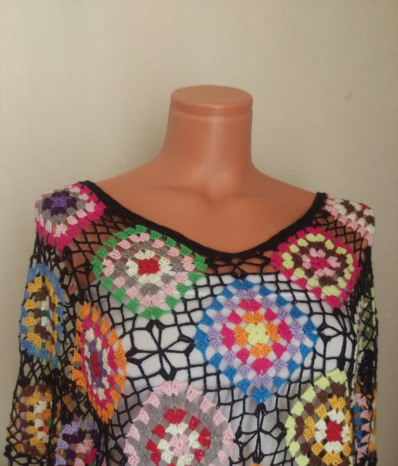 May include: A black crochet top with a colourful geometric pattern. The top is made of a lightweight, breathable fabric and features a loose, flowing fit.