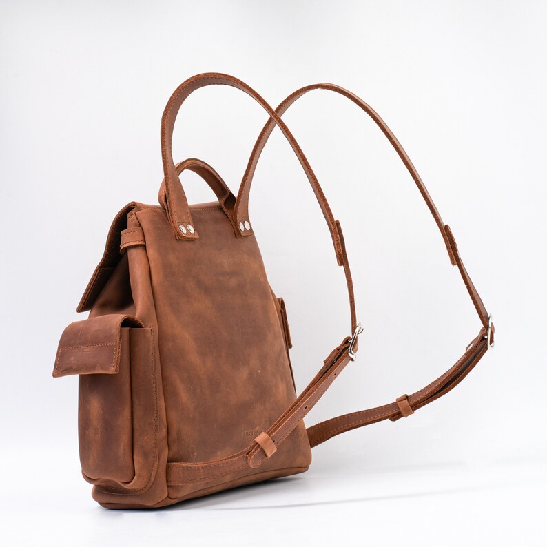 Versatile brown leather backpack featuring adjustable straps and side pockets, perfect for everyday use, with a sophisticated matte finish.