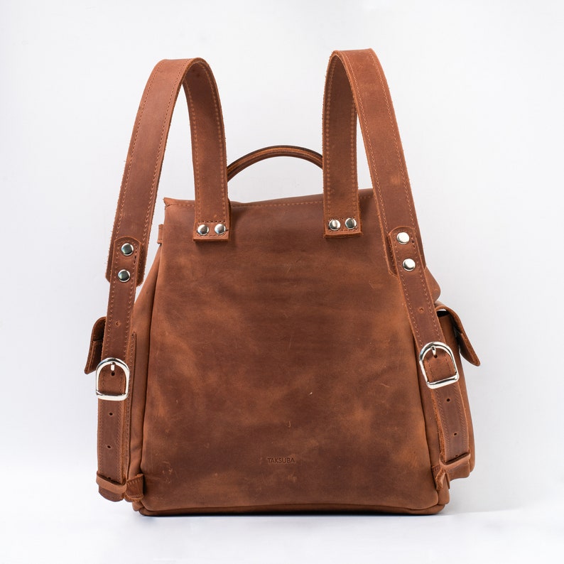 Stylish brown leather backpack view from the back, highlighting adjustable straps and metallic accents for a chic and functional look