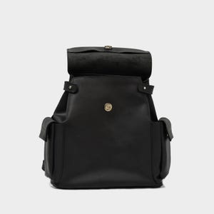 front view of black European leather backpack with flap open, showcasing magnetic snap closure and top-loading main compartment with dual side pockets