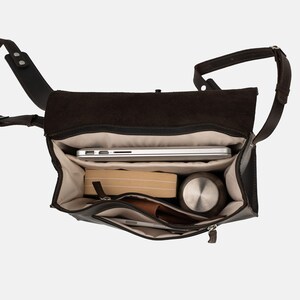 May include: Open view of a dark brown leather messenger bag with a flap closure. Inside, a silver laptop, a book, a stainless steel water bottle, a wallet, and a phone are visible. The bag has a shoulder strap.