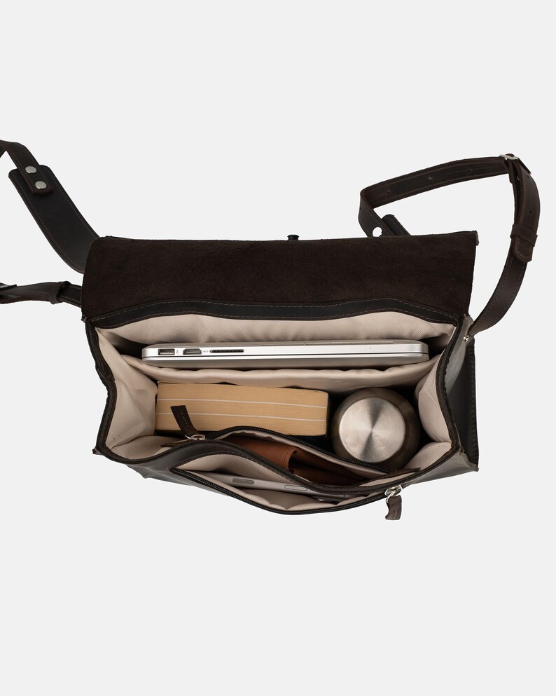 May include: Open view of a dark brown leather messenger bag with a flap closure. Inside, a silver laptop, a book, a stainless steel water bottle, a wallet, and a phone are visible. The bag has a shoulder strap.