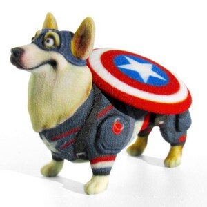 May include: A 3D printed figurine of a corgi dog dressed as Captain America. The dog is wearing a blue and red costume with a white star on the chest and a red, white, and blue shield on its back.