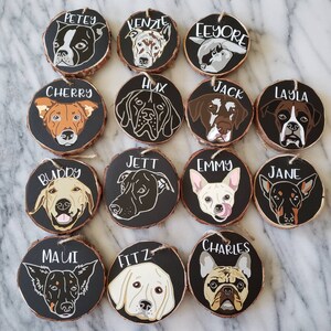May include: Twelve round wooden ornaments with black painted surfaces and white painted dog silhouettes and names. The names are: Petey, Kenzie, Eeyore, Cherry, Hux, Jack, Layla, Buddy, Jett, Emmy, Jane, Maui, Fitz, and Charles.