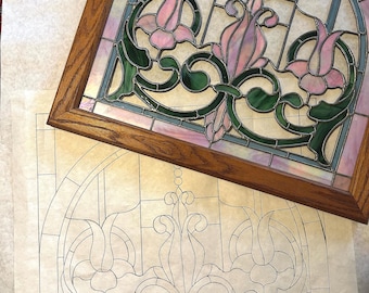 Könnte beinhalten: Ein Buntglasfensterdesign mit einem floralen Motiv aus rosa, grünen und blauen Glasscheiben. Das Design ist in Holz gerahmt und wird von einem Papiermuster begleitet.