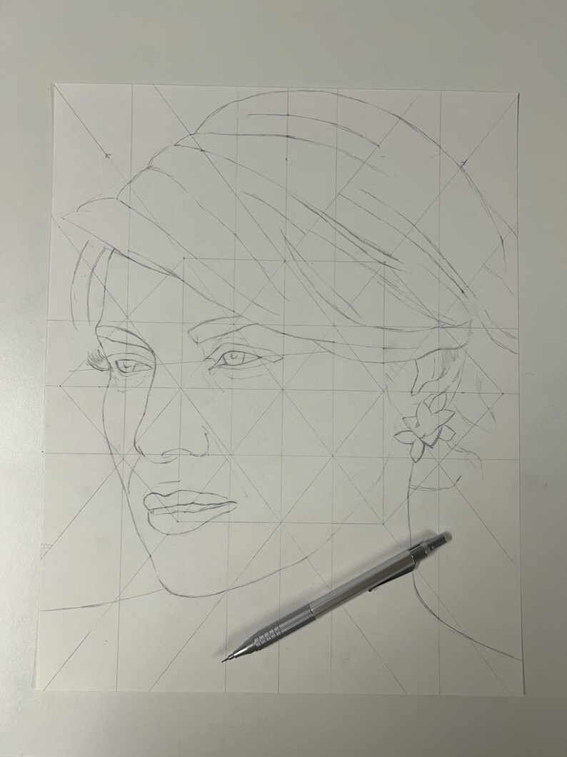 May include: A graphite pencil sketch on white paper featuring a portrait of a person wearing a hat and a floral earring. The drawing includes geometric grid lines for proportion and a mechanical pencil resting across the bottom right corner.