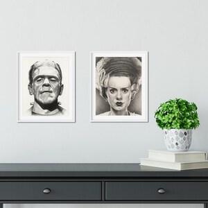 Peut inclure: Deux portraits encadr&eacute;s en noir et blanc style fusain affich&eacute;s c&ocirc;te &agrave; c&ocirc;te. L'impression de gauche repr&eacute;sente un homme avec une t&ecirc;te plate et des boulons au cou. Celle de droite montre une femme avec une coiffure volumineuse et des l&egrave;vres sombres.
