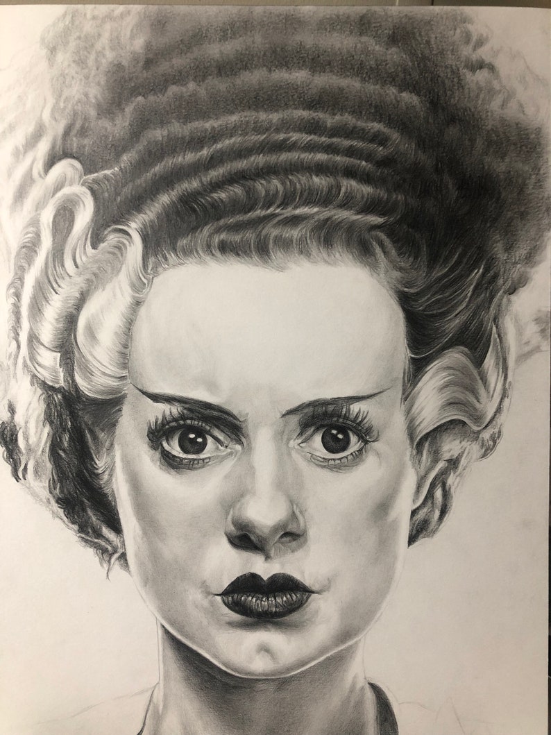 Peut inclure: Un dessin au crayon graphite repr&eacute;sentant une personne avec une coiffure haute et volumineuse, marqu&eacute;e par des m&egrave;ches blanches sur les c&ocirc;t&eacute;s. Le sujet a des sourcils arqu&eacute;s, de longs cils et des l&egrave;vres sombres, dans un style r&eacute;aliste.