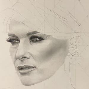 May include: A graphite pencil drawing of a face featuring detailed shading on the eyes, nose, and lips. The portrait includes visible geometric construction lines and grid marks across the forehead and hair area, with a floral earring.