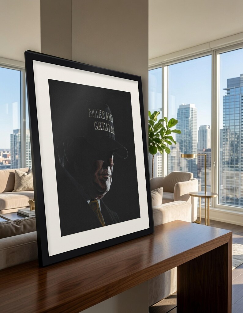 May include: A framed portrait print featuring a side profile of a person wearing a dark cap with the text MAKE AMERICA GREAT AGAIN in white lettering. The image uses high-contrast lighting, casting deep shadows across the face and neck.