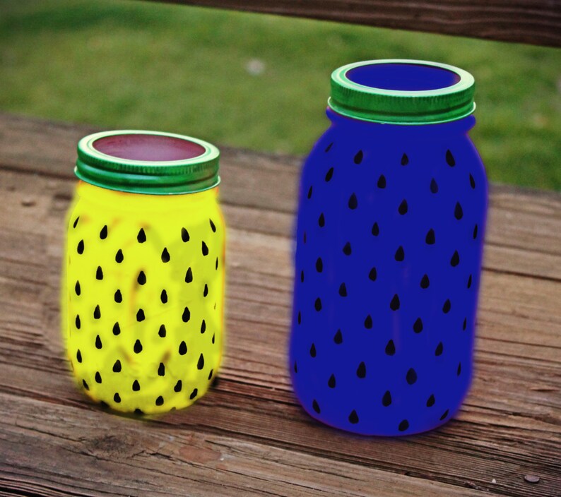 May include: Two glass jars painted to look like watermelons. One jar is yellow with black watermelon seeds and the other is blue with black watermelon seeds.