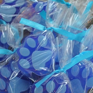 K&ouml;nnte beinhalten: Blaue Seifen in Pfotenform, verpackt in durchsichtigen Cellophanbeuteln mit blauen Schleifen.