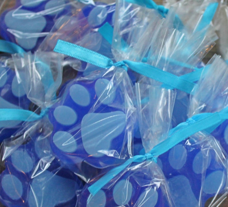 K&ouml;nnte beinhalten: Blaue Seifen in Pfotenform, verpackt in durchsichtigen Cellophanbeuteln mit blauen Schleifen.