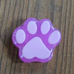K&ouml;nnte beinhalten: Eine violette Seife in Form eines Pfotenabdrucks mit wei&szlig;en Pfotenballen.