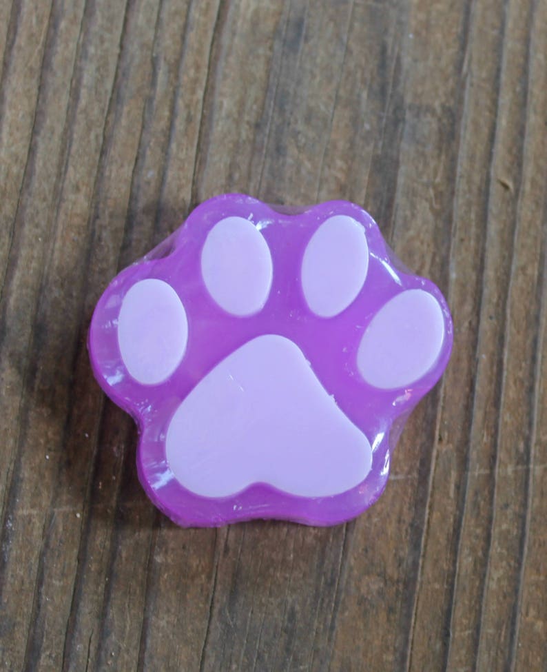 K&ouml;nnte beinhalten: Eine violette Seife in Form eines Pfotenabdrucks mit wei&szlig;en Pfotenballen.
