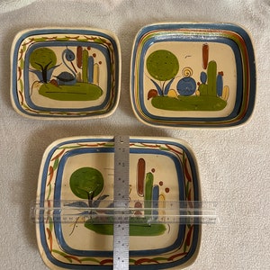 May include: Three ceramic rectangular serving dishes with blue, green, and brown painted designs. The dishes are hand-painted with a variety of motifs, including trees, birds, and geometric patterns. The largest dish measures 12 inches in length.