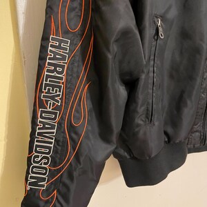 May include: Black bomber jacket with orange flame detailing and the Harley-Davidson logo on the sleeve.