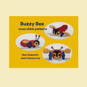 May include: Three cross stitch patterns of a Buzzy Bee toy, a popular toy in New Zealand. The patterns are in a yellow oval frame with a white background. The text "Buzzy Bee cross stitch patterns" is at the top of the image. The text "New Zealand's most famous toy" is at the bottom of the image.