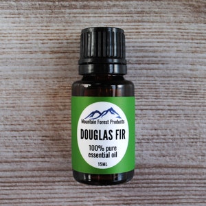 Peut inclure: Une bouteille de 15 ml d'huile essentielle de sapin de Douglas avec une étiquette verte indiquant "Mountain Forest Products" et "100% pure huile essentielle".