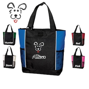 May include: A black tote bag with a blue and white accent. The bag has a mesh pocket on the side and a white embroidered dog with the name "Allison" underneath. The bag is shown with other tote bags in different colors: red, pink, green, and white.