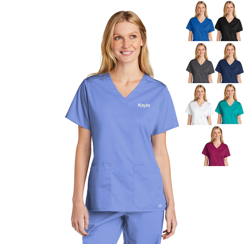 May include: A light blue scrub top with a v-neck and a pocket on the left side. The top has the name "Kayla" embroidered on the right side. The image also shows a variety of other scrub top colors.
