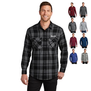 May include: A black and gray plaid flannel shirt with long sleeves and a button-down collar. The shirt has two chest pockets and the name "Scott" embroidered on the right pocket.